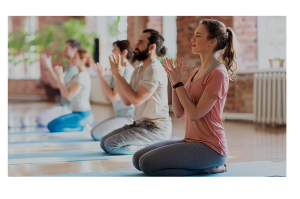 Yoga class pictured on their knees with a blonde female at the front